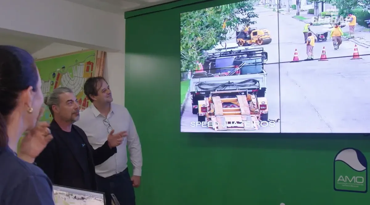 Equipe da AMO Pedra Branca acompanhando a operação do bairro em um painel de vídeo